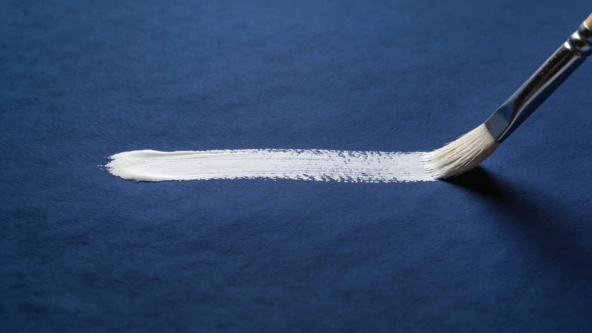 A brush stroke of white pigment on blue paper