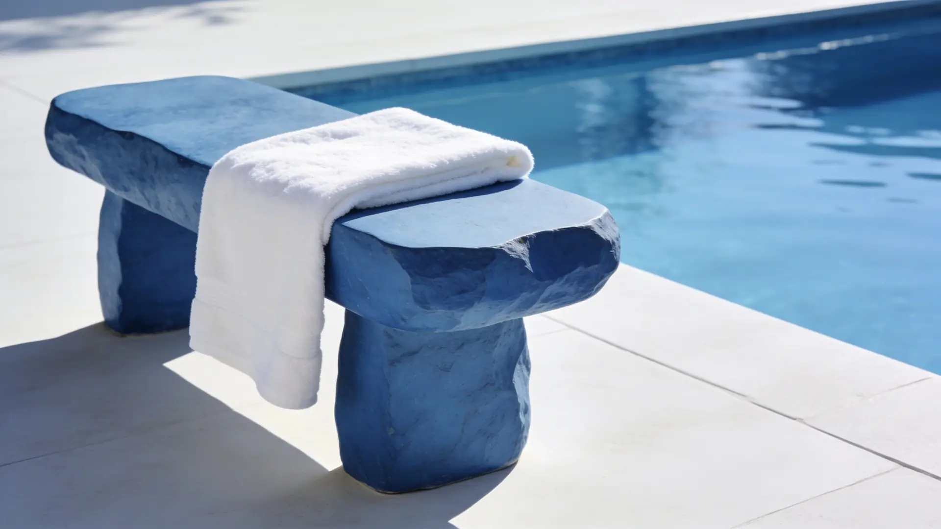 A folded white towel on a blue stone bench by water — illustrative image for back acne