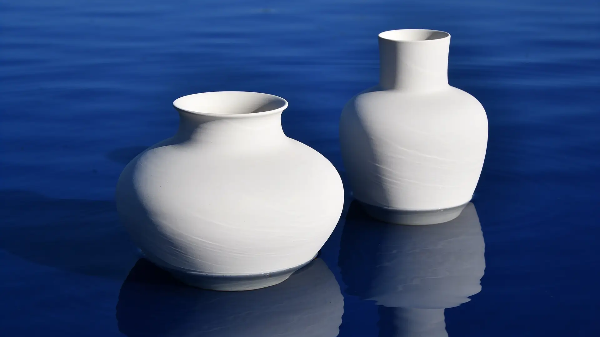 Two white vessels of slightly different heights reflected in water — illustrative image for facial asymmetry