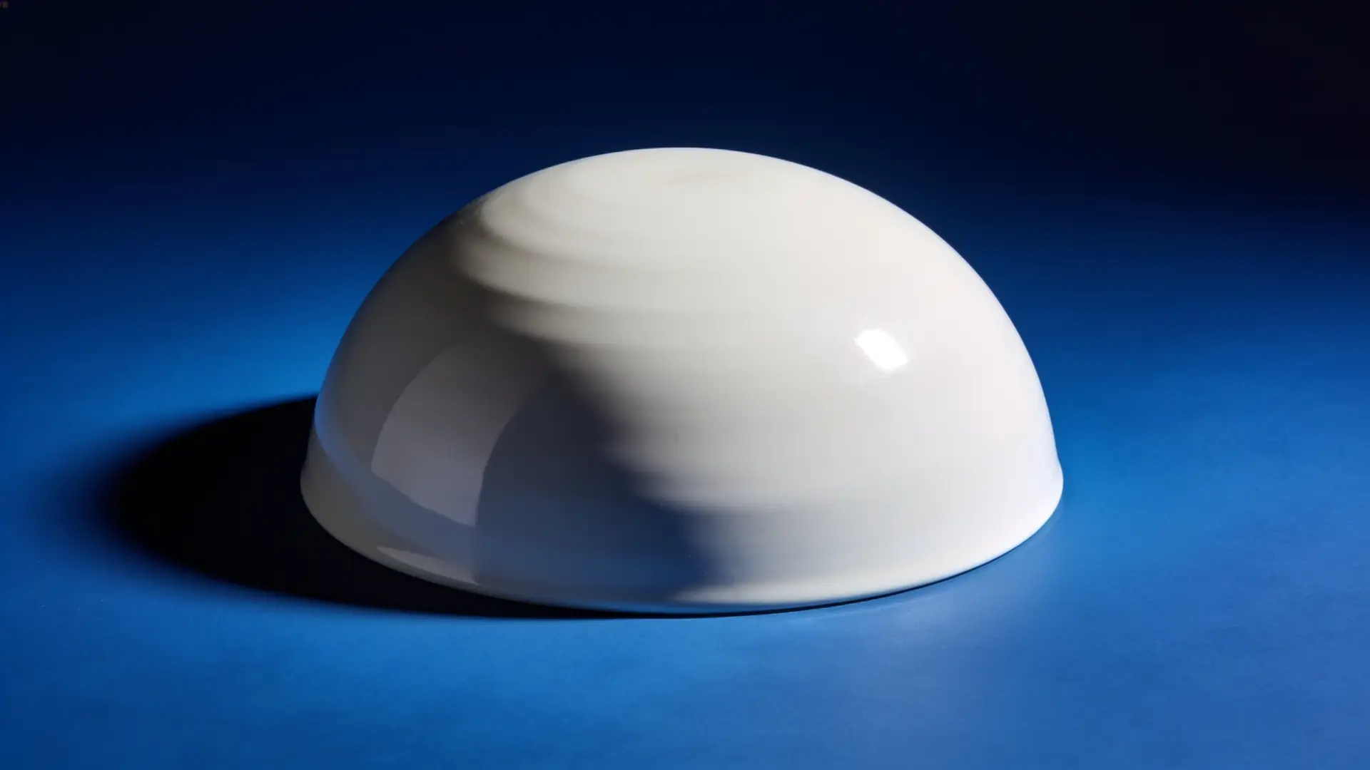 A smooth white porcelain dome against deep blue — illustrative image for forehead filler