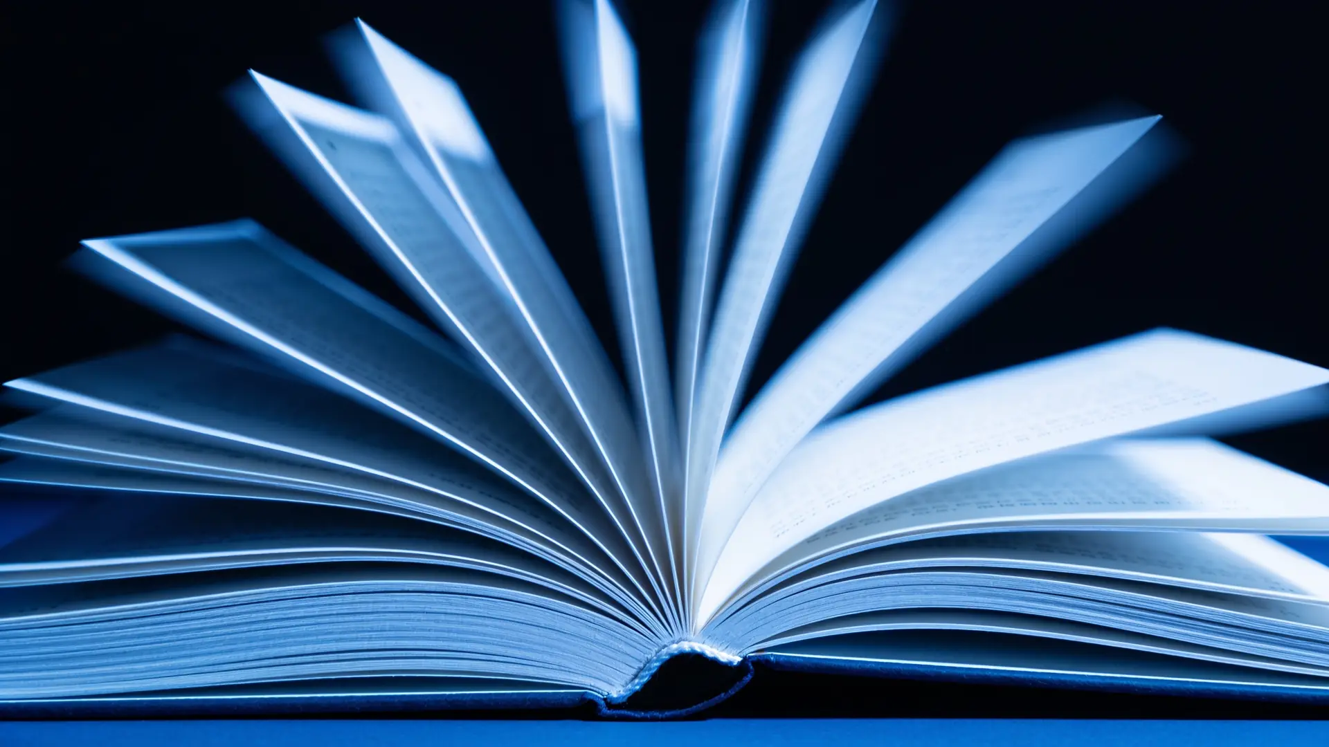An open book with fanning pages in cool blue light — illustrative image for the glossary