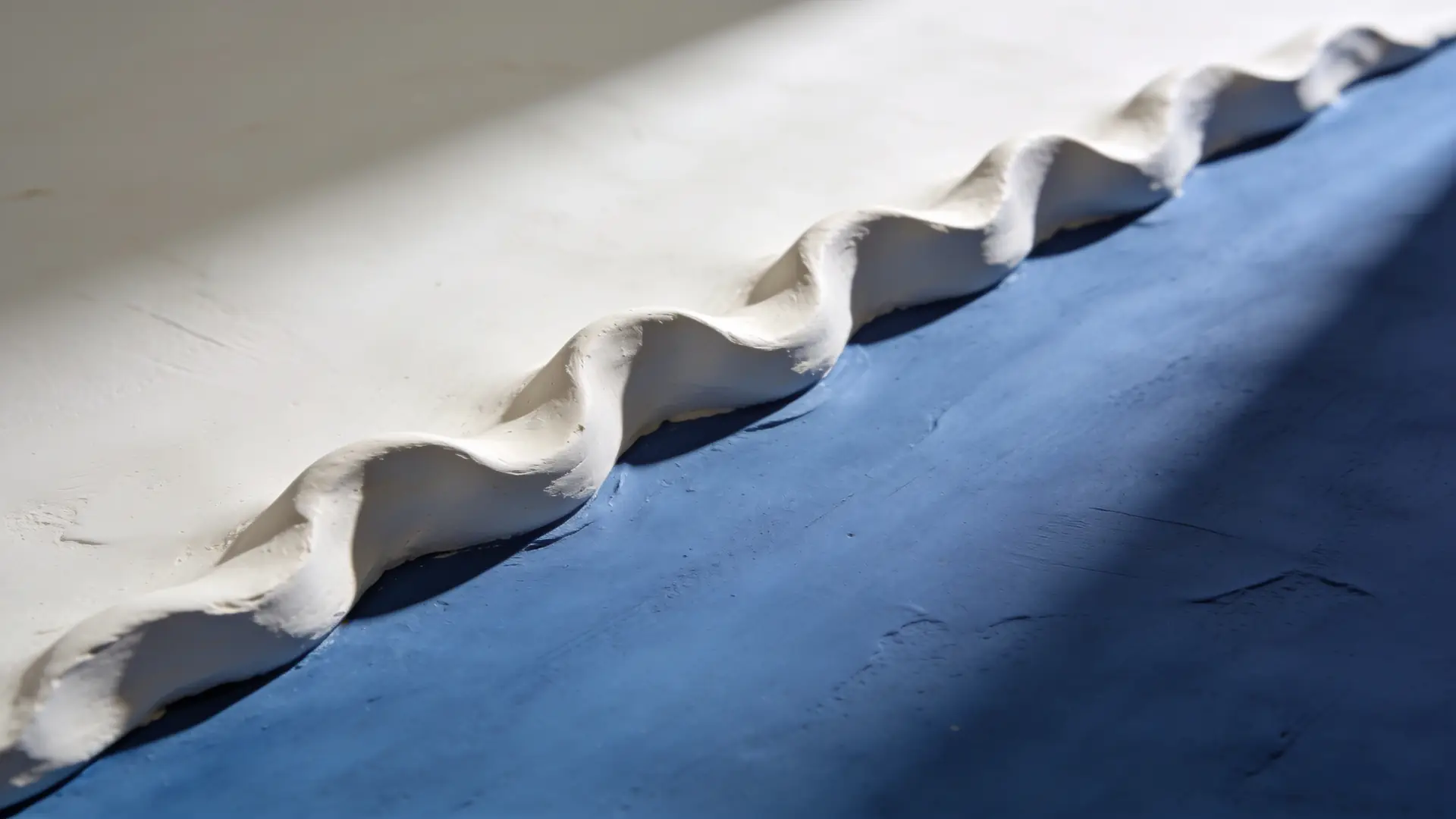 A raised ridge sculpted in white clay on blue — illustrative image for keloid treatment