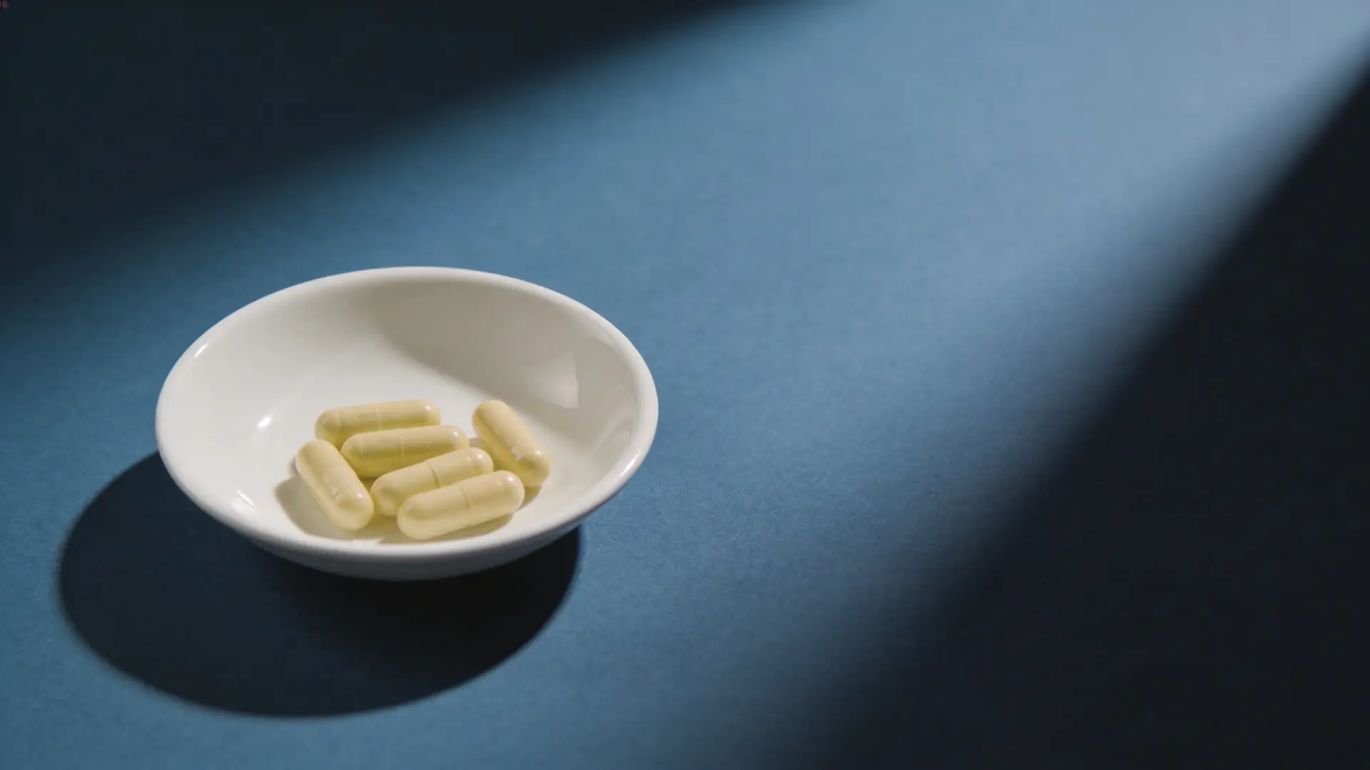 Pale yellow capsules in a white porcelain dish — illustrative image for oral antibiotics for acne