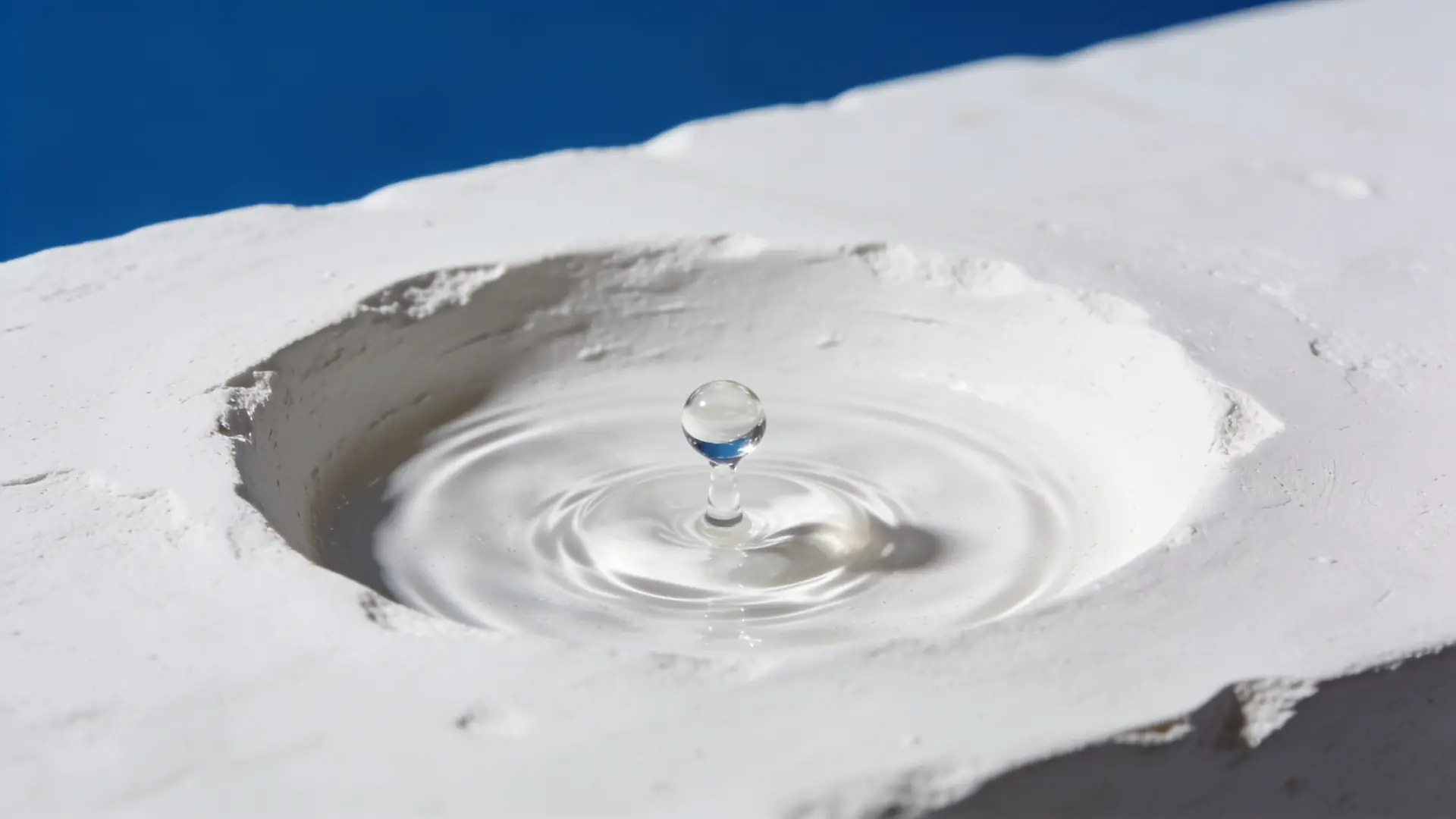 A single droplet falling into a small well in white plaster — illustrative image for TCA CROSS